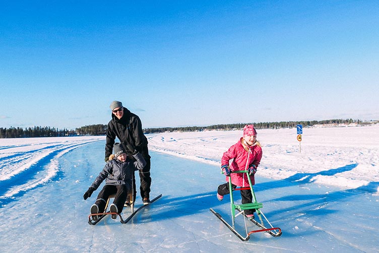 Kinder auf Schlitten während einem Finnland-Urlaub im Winter