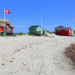 Bunte Häuser am weißen Sandstrand – das ist Familienurlaub in Dänemark am Meer