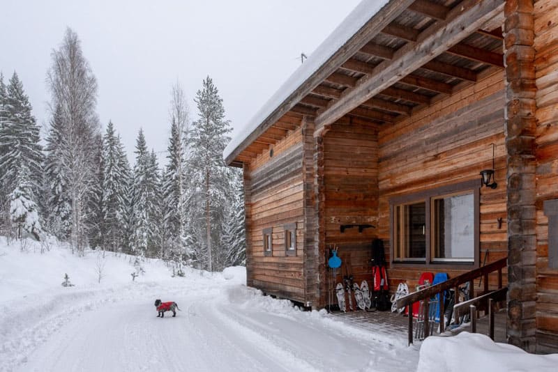Lodge mit HotPot im Schnee an verschneiter Straße in Finnland