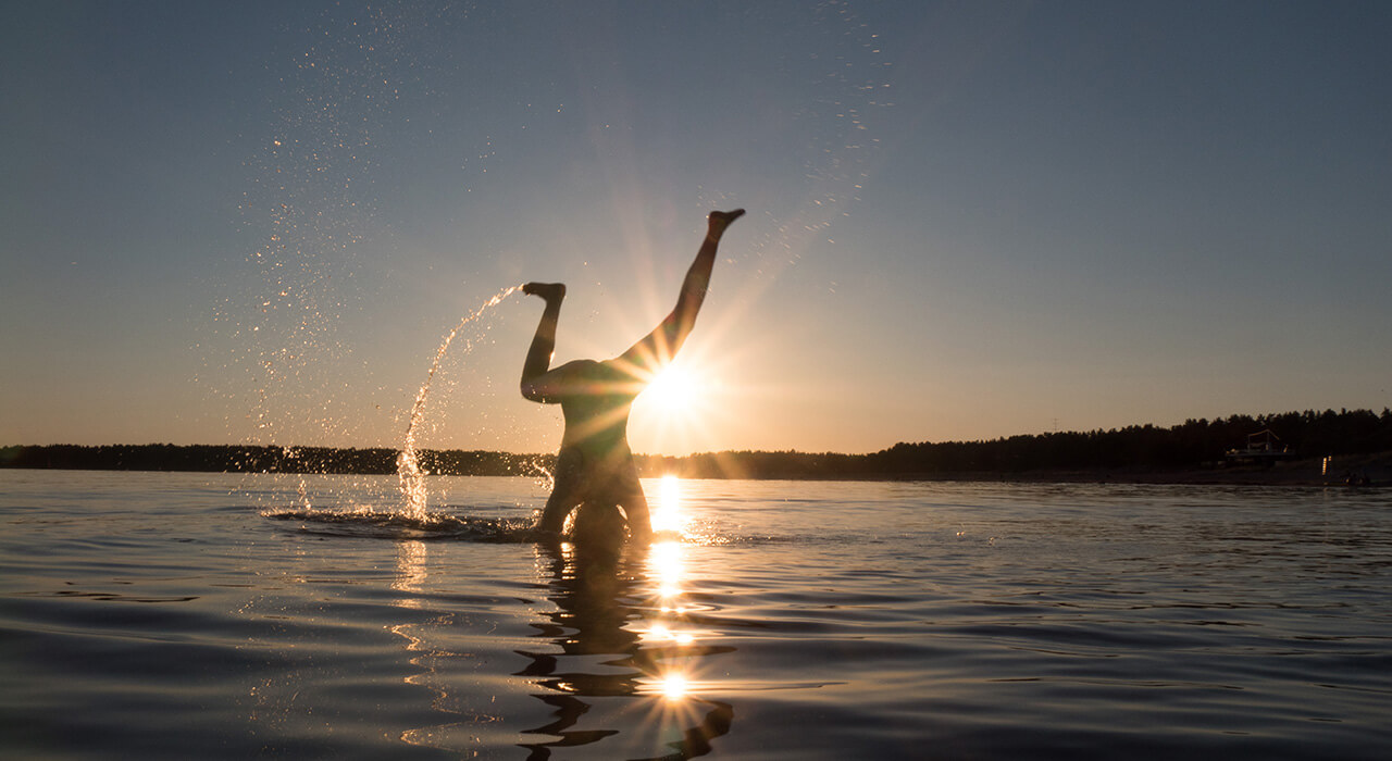 Ein Kind spielt im Sonnenuntergang im Wasser – Eindruck aus einem Sommerurlaub in Finnland.