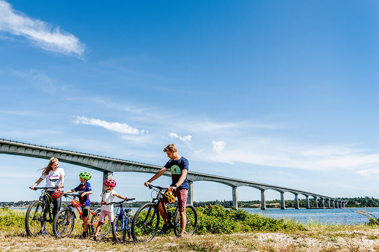 Familie mit Fahrrädern vor einer großen Brücke.