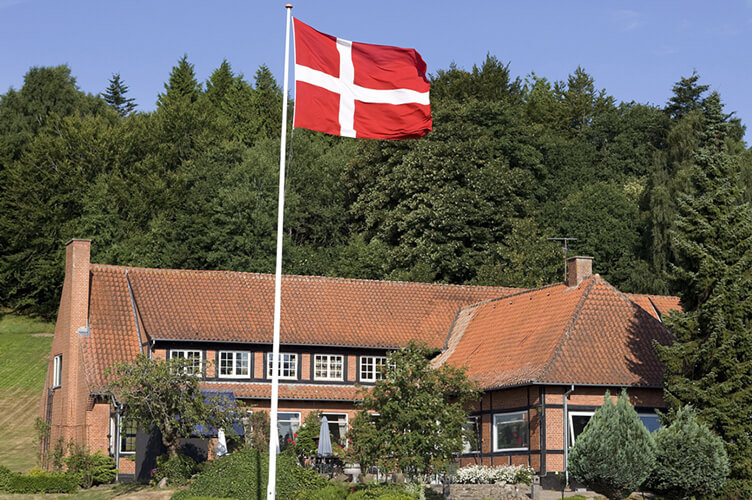 Großes rotes Backsteinhaus hinter einen dänischen Flagge.
