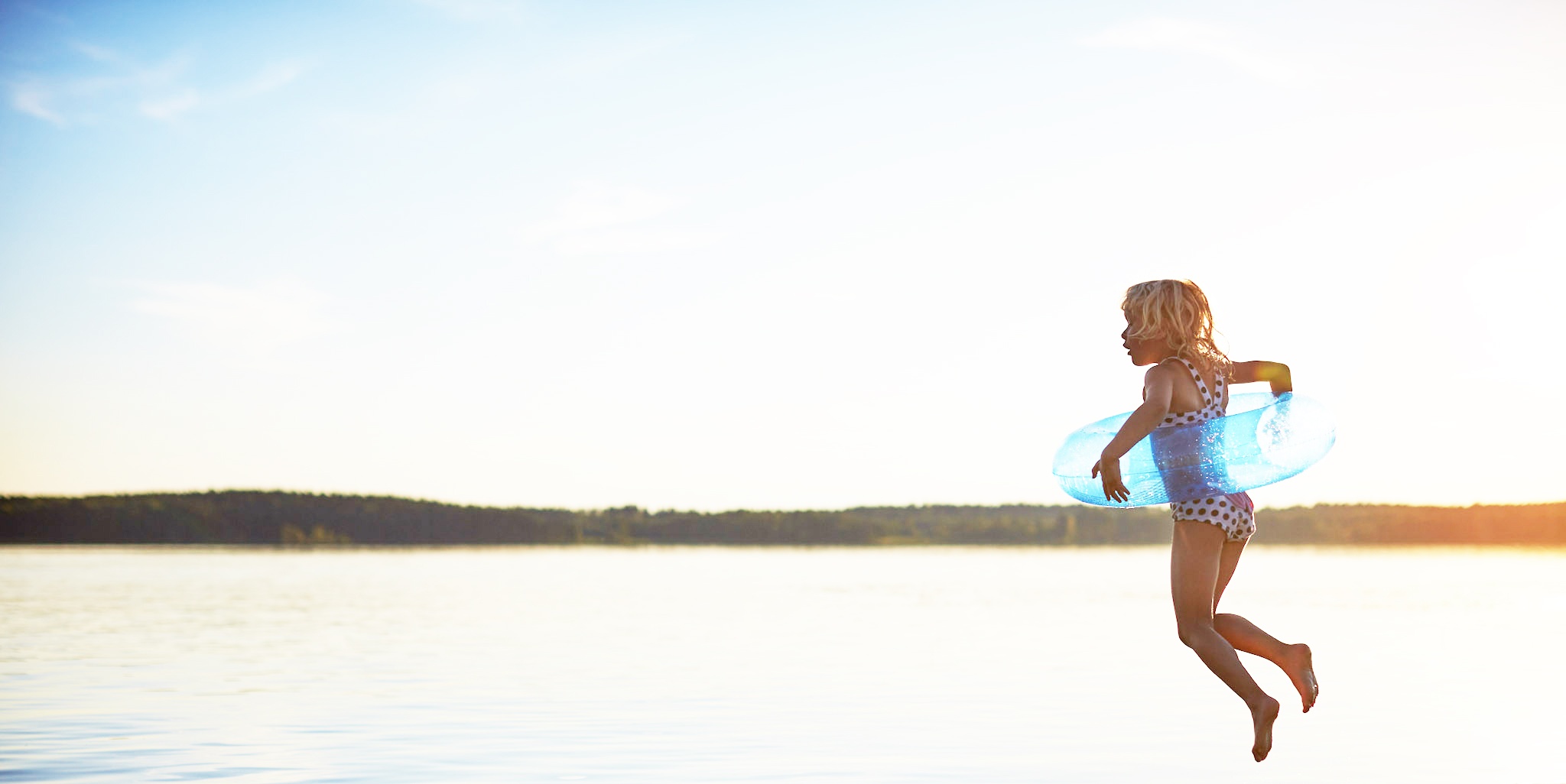 Ein Kind springt in einen See in Skandinavien 