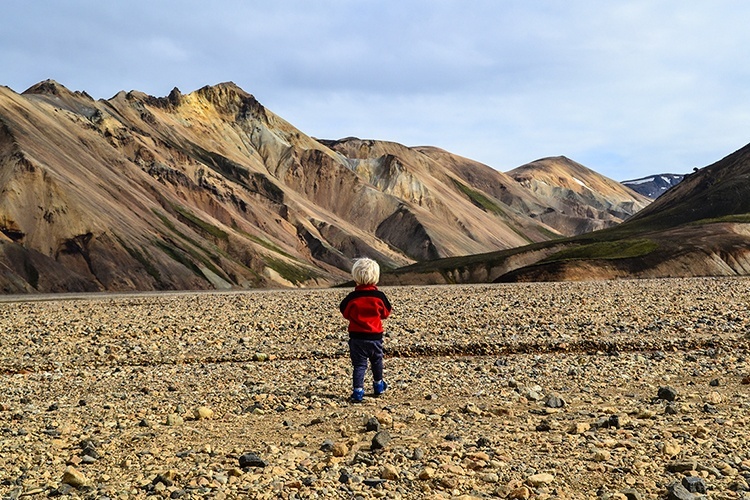 Ein Kind steht in Island vor einer rauen Vulkanlandschaft.
