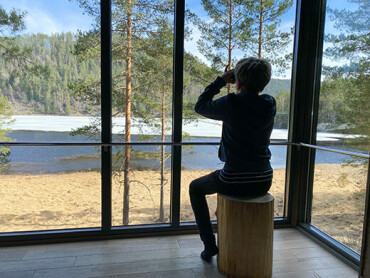 Ein Kind sitzt im Baumhaus und schaut aus dem Fenster auf das Wasser.
