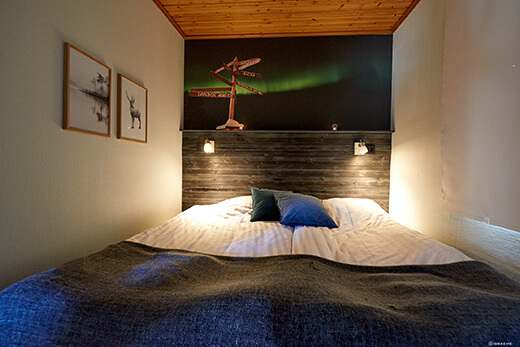 Blick auf ein von Lampen beleuchtetes Doppelbett.