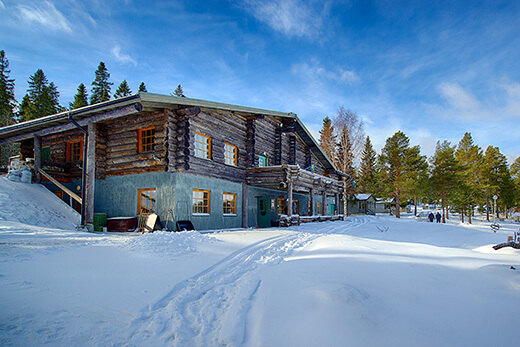 Seitliche Ansicht der Lodge bei blauem Himmel und mit viel Schnee.