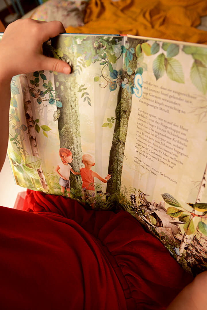 Ein Kind liest im Kinderbuch Garmans Geheimnis.