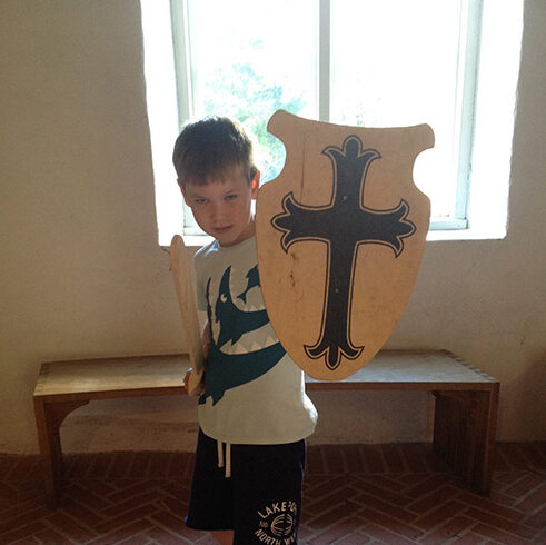Ein Junge hält sein Ritterschild hoch.