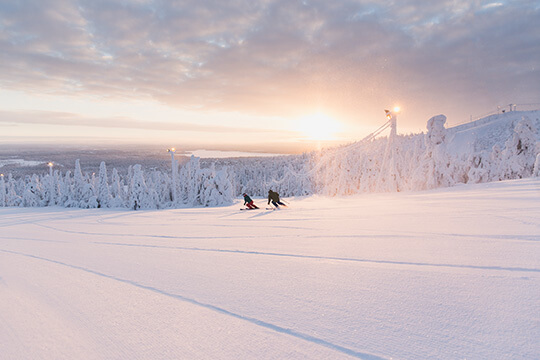 Zwei Skifahrer fahren in der Abendsonne.