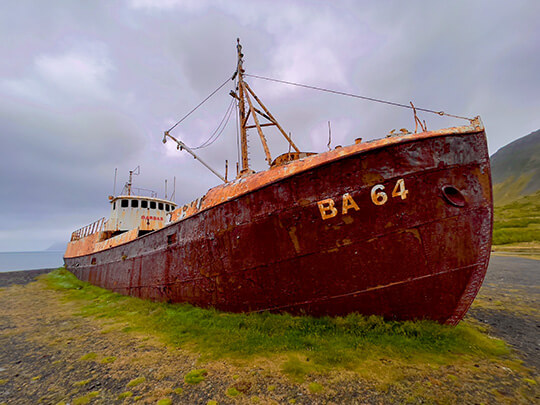Ein altes verrostetes Schiffswrack, dass auf dem Land liegt.