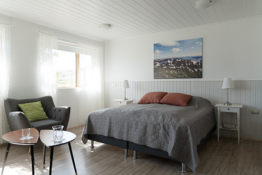 Ein helles Zimmer mit Doppelbett und Sitzecke.