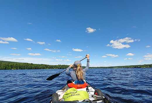 Eine Frau sitzt im Kanu und fährt über einen See in Värmland.
