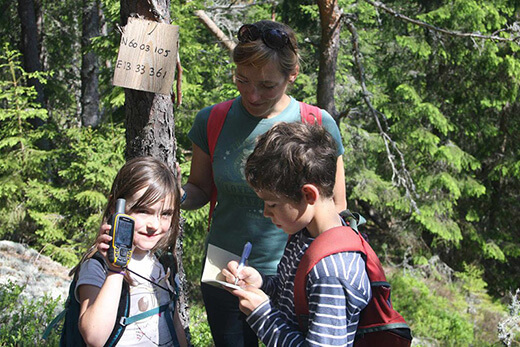 Zwei Kinder und eine Frau orientieren sich anhand GPS Daten.