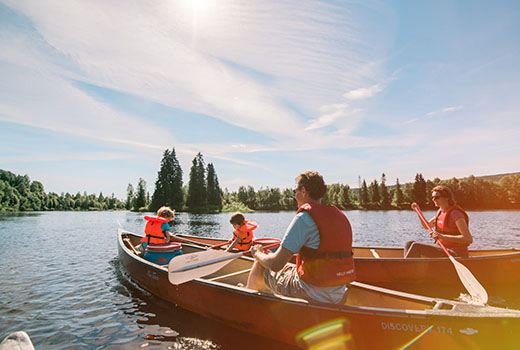 Eine Familie paddelt in zwei Kanus über einen See.