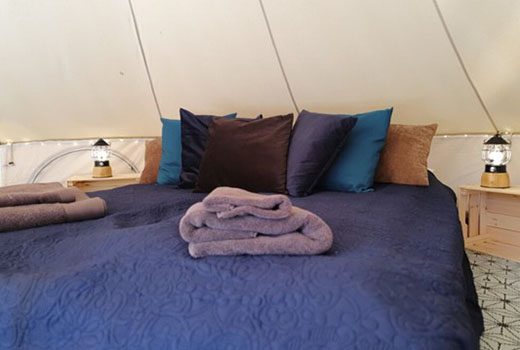 Ein Doppelbett in einem gemütlichen Zelt.