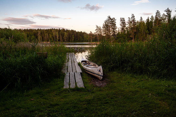 Ein Kanu liegt an einem Steg an einem See.