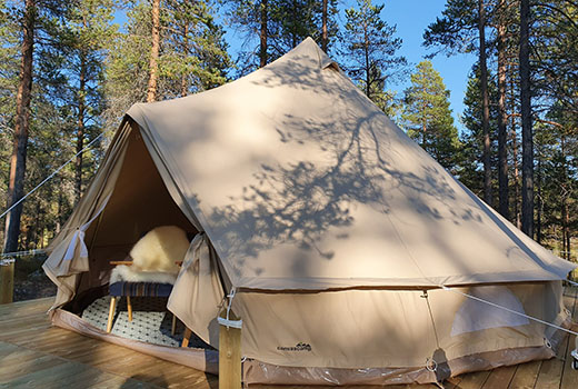 Ein Zelt mit Terrasse im Wald.