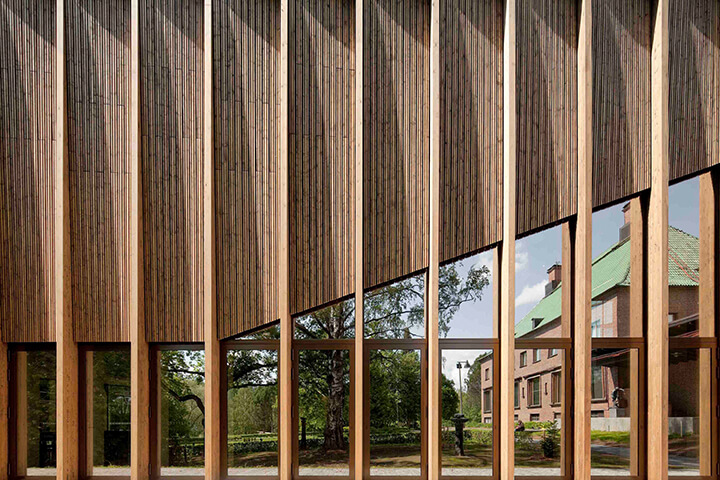 Holzfassade mit breiten Ausschnitten und Blick auf dahinterliegendes Haus