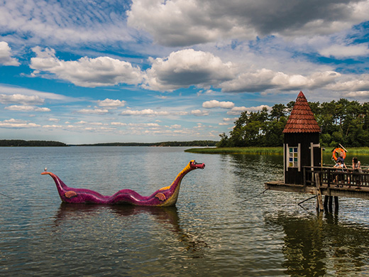 Lila Holzdrache treibt im See vor einem Steg