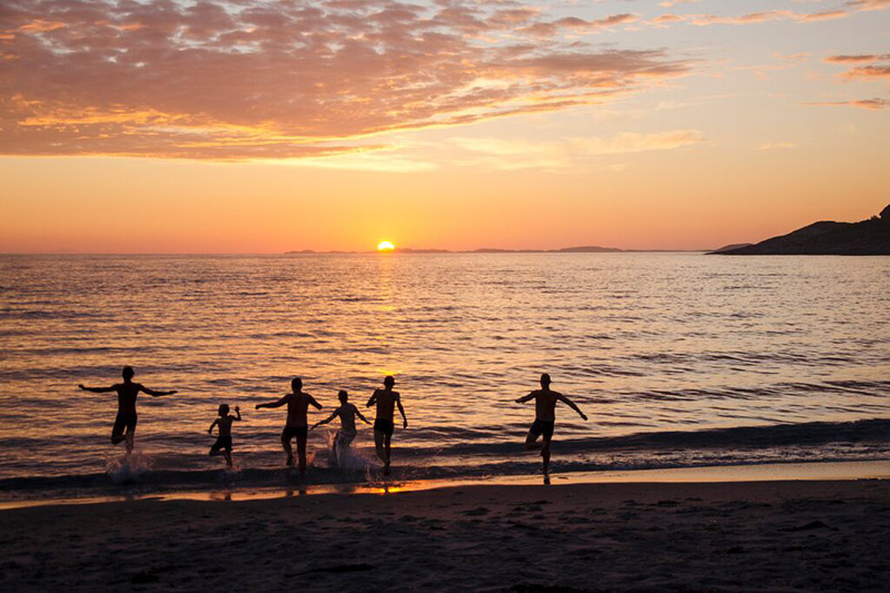 Familie rennt ins Meer bei Sonnenuntergang
