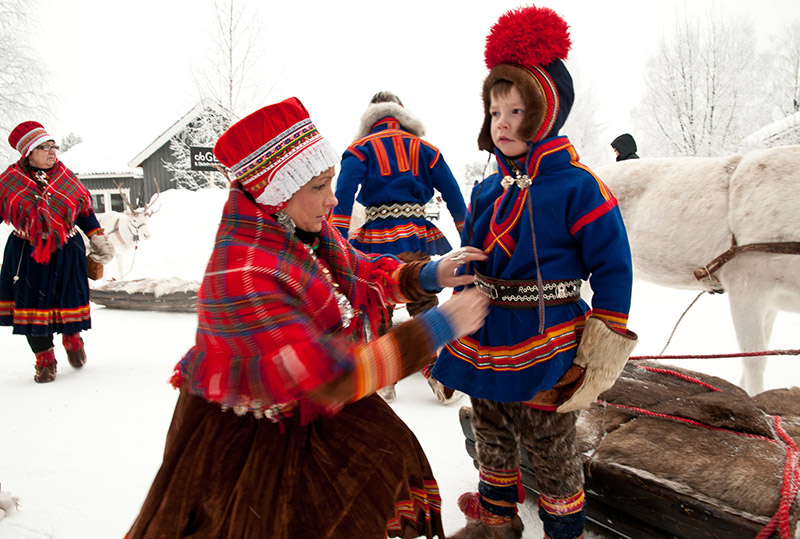Frau in Sami-Tracht richtet die Sami-Tracht eines kleinen Jungen