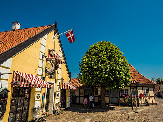 An einem gelben Haus weht die dänische Flagge.