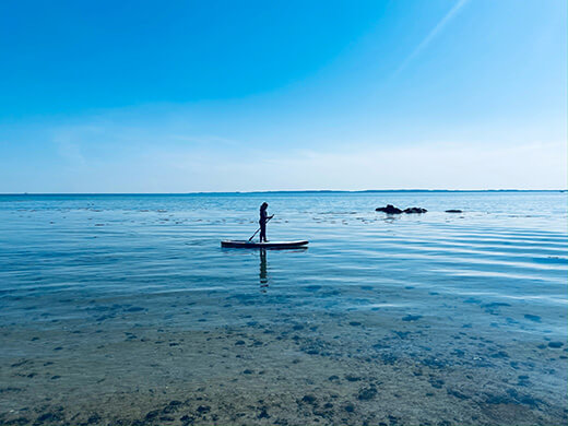 Ein Mädchen paddelt mit einem SUP-Board auf dem klaren Wasser.
