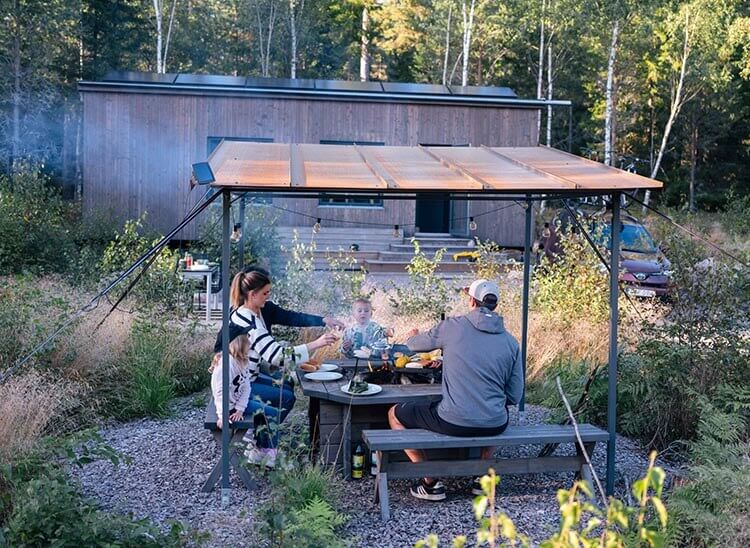 Eine Familie grillt auf dem Grillplatz vor dem Tinyhaus.