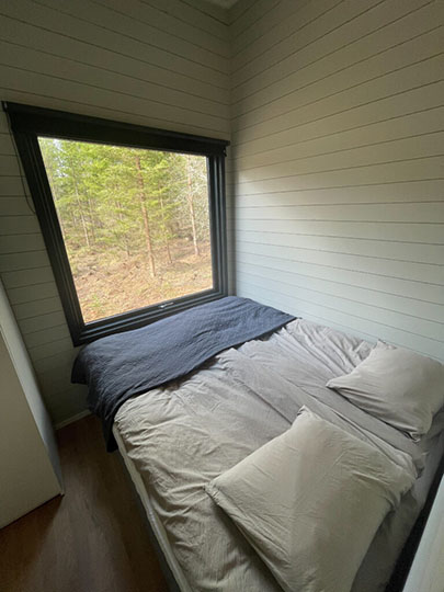 Der Schlafbereich eines Tinyhauses mit Blick in den Wald.