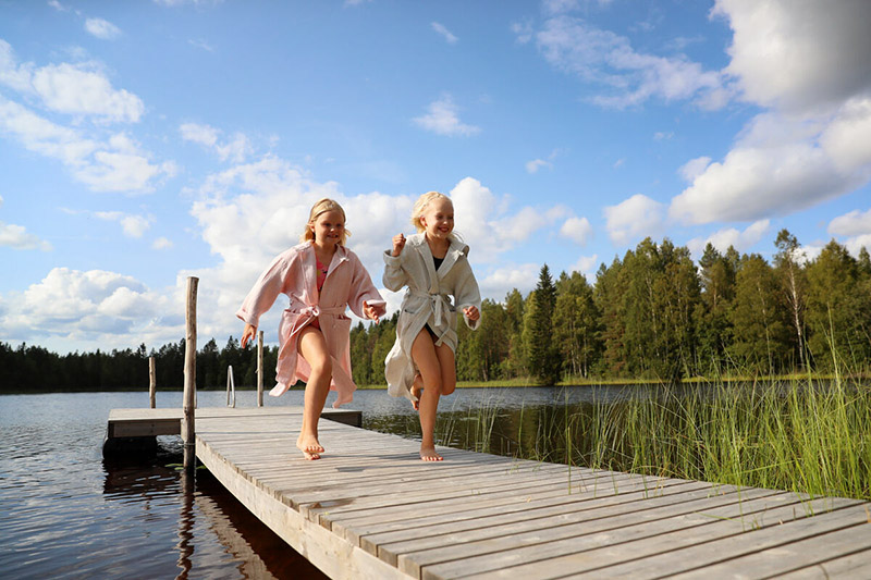 Zwei Mädchen rennen über einen Steg und lachen.