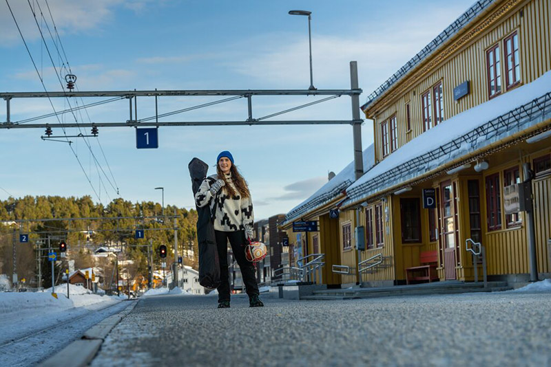 Eine junge Frau steht am Bahnsteig in Winterkleidung.