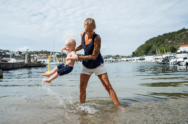 Eine Mutter spielt mit ihrem kleinen Kind im Wasser.