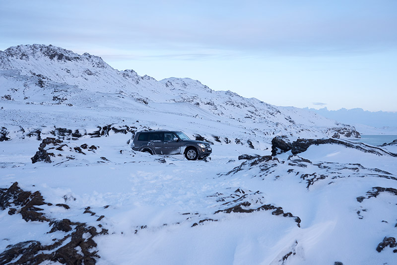 Ein graues Auto steht in einer verschneiten Winterlandschaft.