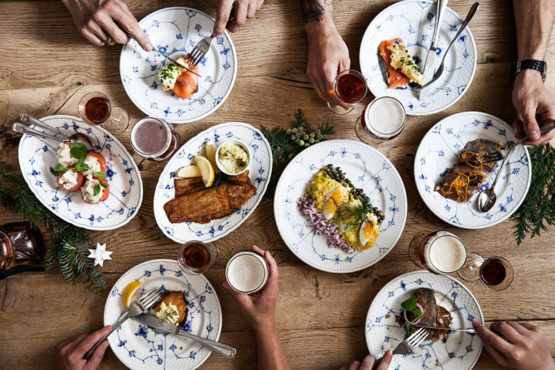 Ein Tisch von oben mit mehreren Tellern auf denen verschiedene Variationen von dänischen Butterbroten zu sehen sind.