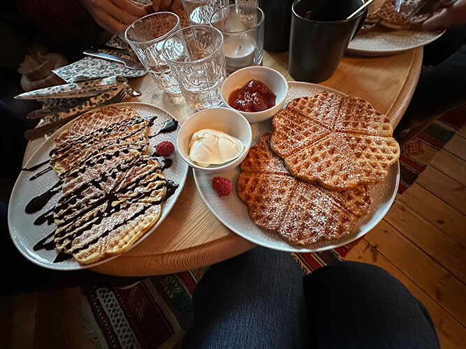 Ein gedeckter TIsch mit zwei großen Tellern auf denen herzförmige Waffeln liegen. 