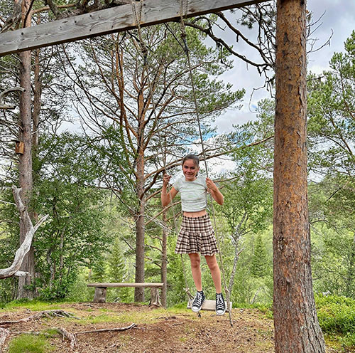 Ein Mädchen steht auf einer Schaukel im Wald