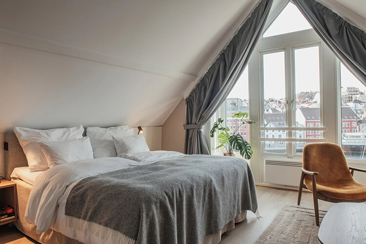 Ein großes Doppelbett in einem Hotelzimmer mit Aussicht auf den Hafen von Stavanger.
