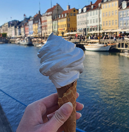 Ein Softeis in der Waffel vor einer bunten Häuserkette.