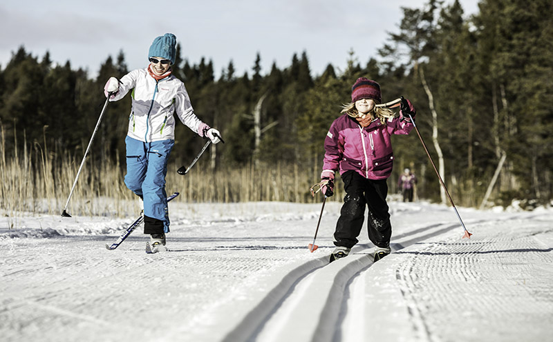 Zwei Kinder mit Skiern beim Crosscountry Skifahren.