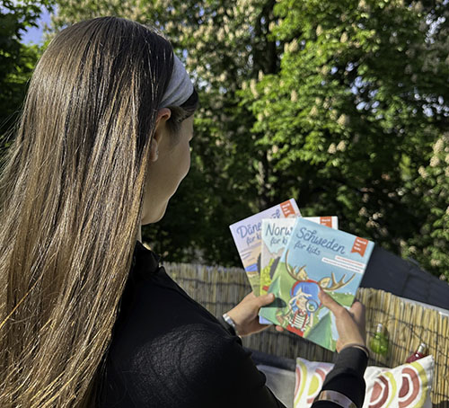 Ein Mädchen mit braunen Haaren hält die drei World for kids Reiseführer in der Hand.