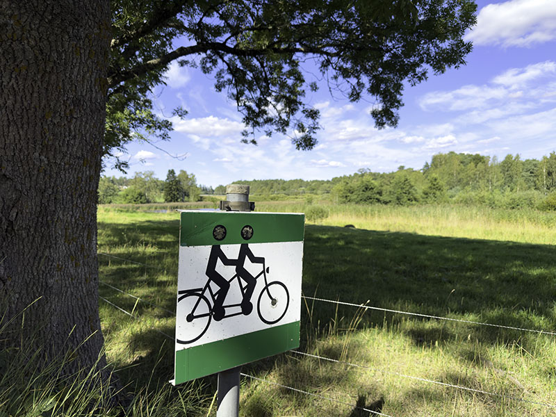 Ein kleines Hinweisschild am Wegrand das den Fahrradweg kennzeichnet.