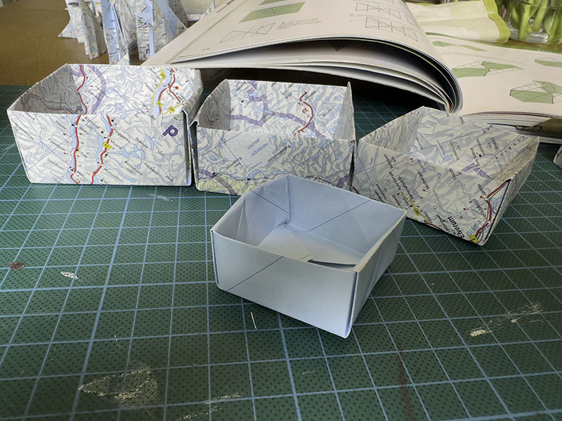 Vier Papierschachteln aus alten Landkarten gefaltet.