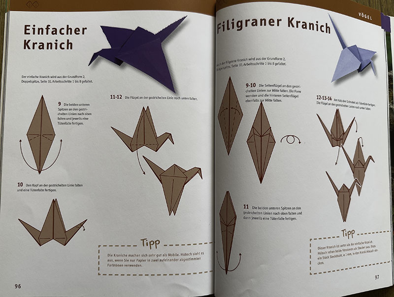 Seite aus einem Buch mit einer Anleitung zum Falten zweier Kranich-Varianten.