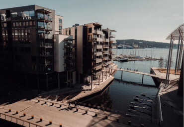 Blick auf moderne Wohngebäude am Wasser mit Stegen und Segelbooten im Hafen von Oslo.