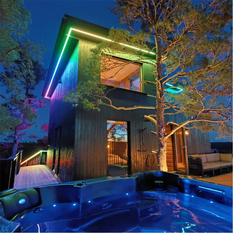 Ein bunt beleuchtetes Baumhaus mit einem Baum und einem Jacuzzi.