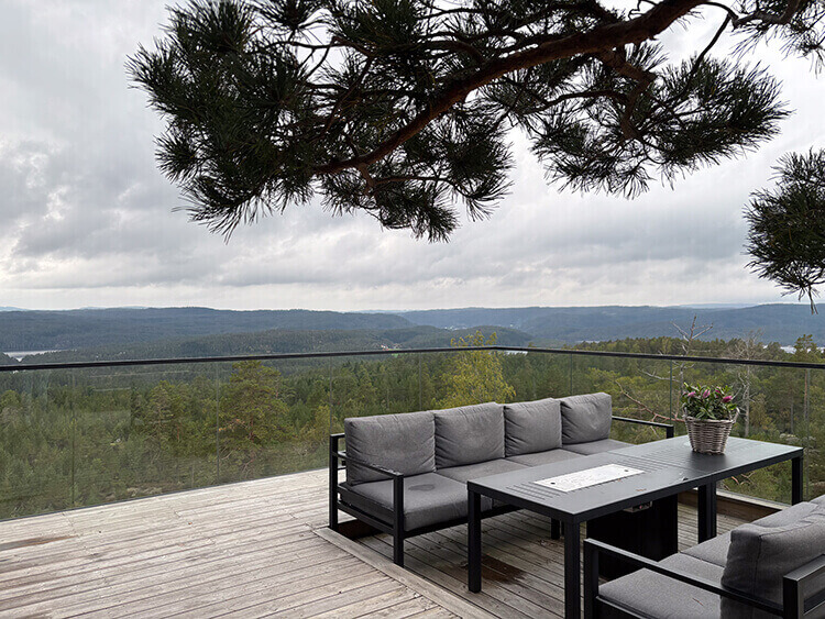 Terrasse mit Sitzgelegenheit und Ausblick über Baumwipfel.