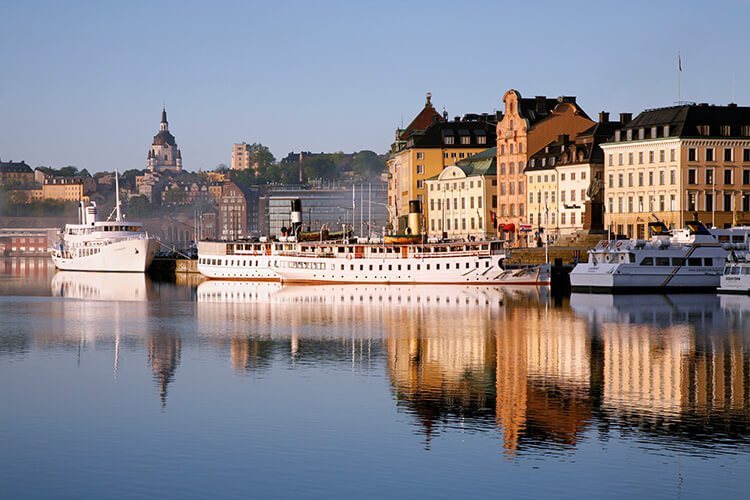 Stadtsilhouette von Stockholm mit mehreren angelegten Passagierschiffen und historischen Gebäuden im Hintergrund