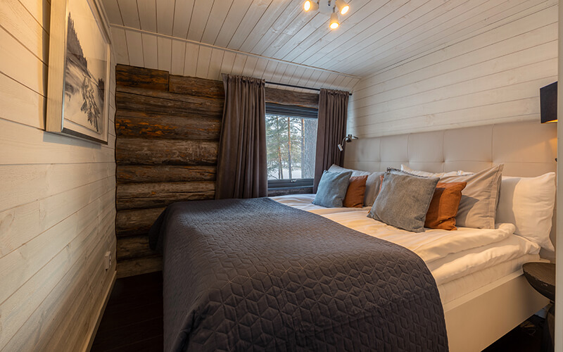 Ein großes Doppelbett mit vielen Kissen in einem holzverkleideten Raum.