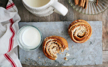 Zwei Zimtschnecken auf einem Brett mit einem Glas Milch.